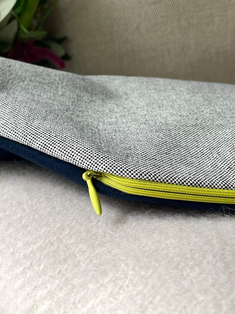 Detailansicht einer handmade Wärmflasche von HETTI. mit Fokus auf die beiden Baumwollstoffe in schwarz-weiß und dunkelblau und den neon-gelben Reißverschluss 