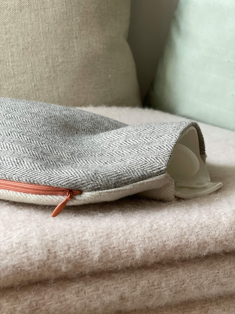 Schöner weicher Wärmflaschenbezug KAT aus Wolle und Leinen in beige und grau mit rosa Reißverschluss, dekoriert auf eine rosé Wolldecke
