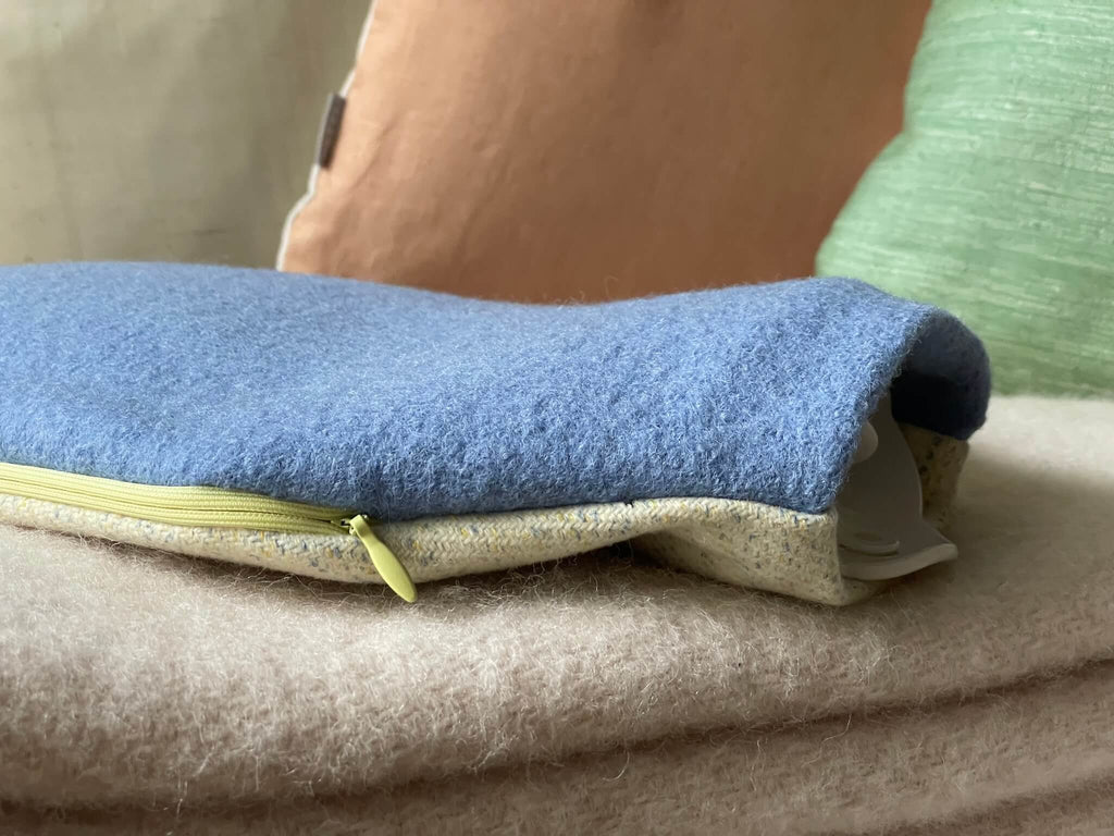 Nahaufnahme der weichen Schurwolle des Wärmflaschenbezugs VIV – hochwertige Naturfaser in Blau und Beige mit gelb-blauem Muster.